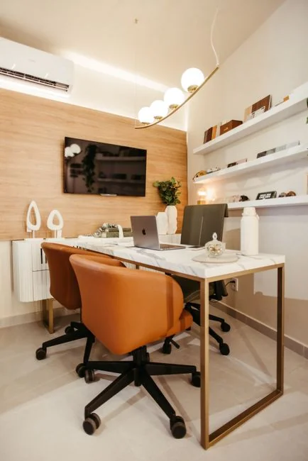 Un professionnel du nettoyage en combinaison rouge aspire un salon moderne avec un aspirateur jaune.
